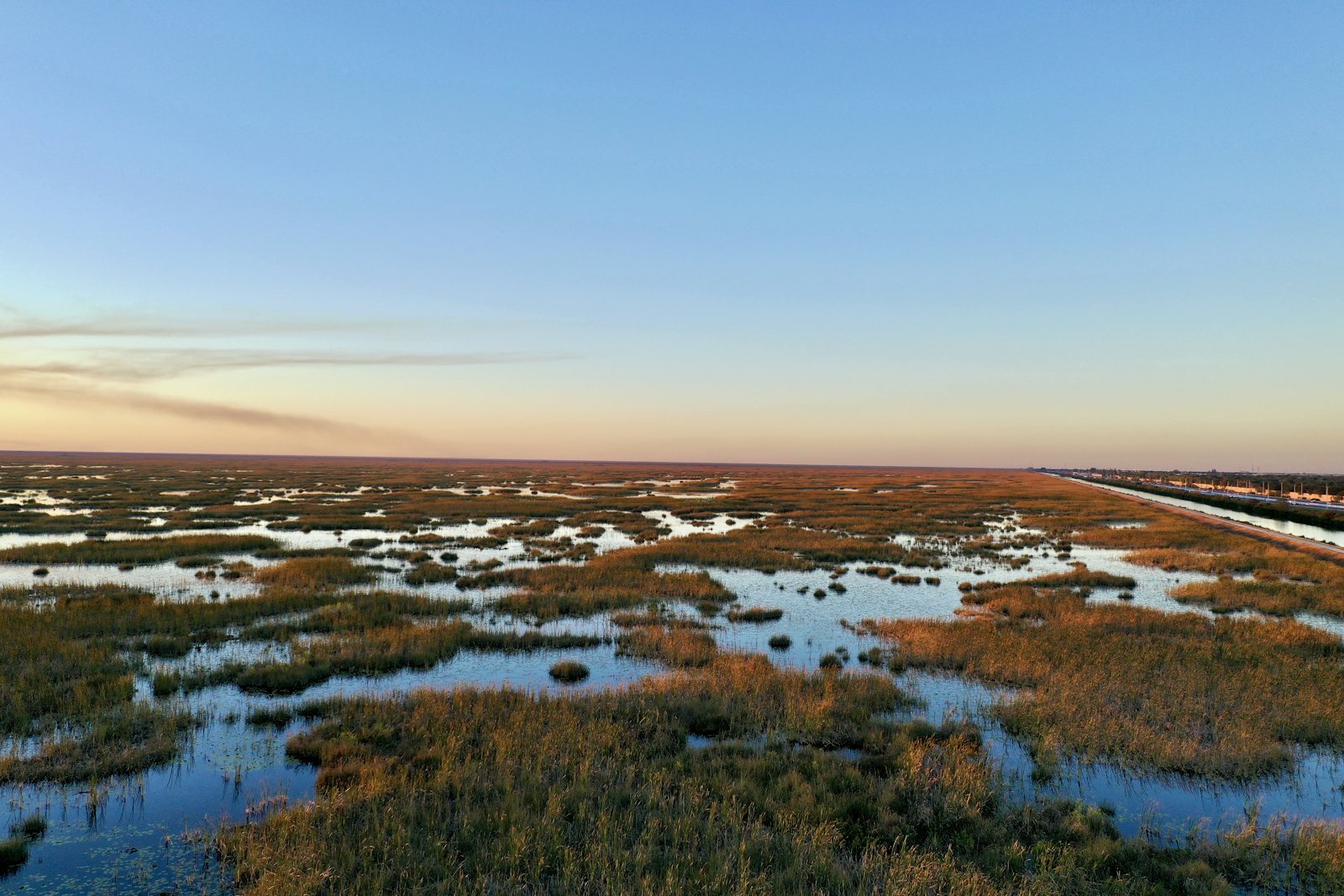 Expansive wetland landscape under a clear sky at dusk
