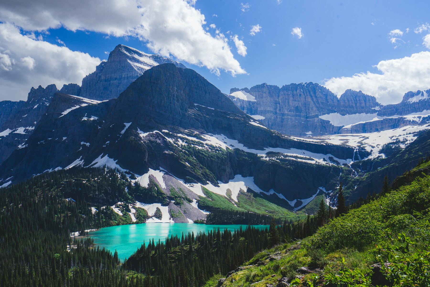 Trail high above a turquoise glacial lake ringed by peaks